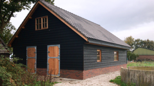 Prefab schuur met een zwart houtmotief.